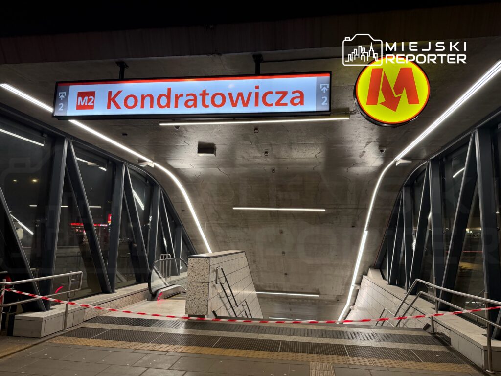 Stacja metra "Kondratowicza" z zamkniętym wejściem, otoczona taśmą ostrzegawczą i nowoczesnym oświetleniem.