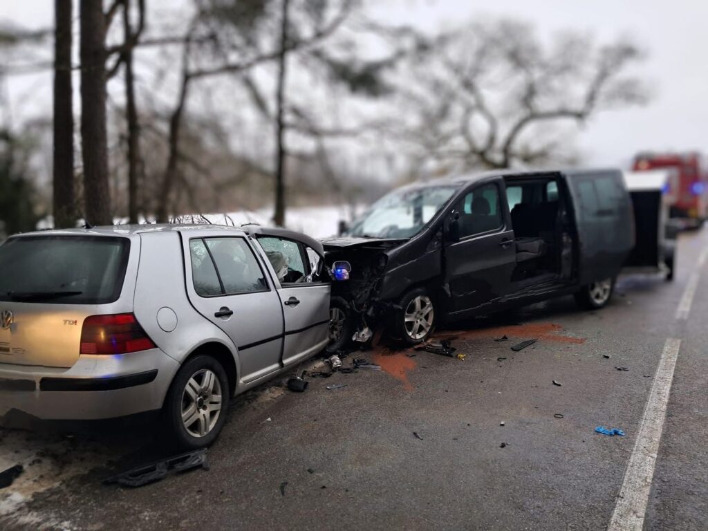 Dwa uszkodzone samochody osobowe po zderzeniu na drodze, otoczone odłamkami i śladami płynów.