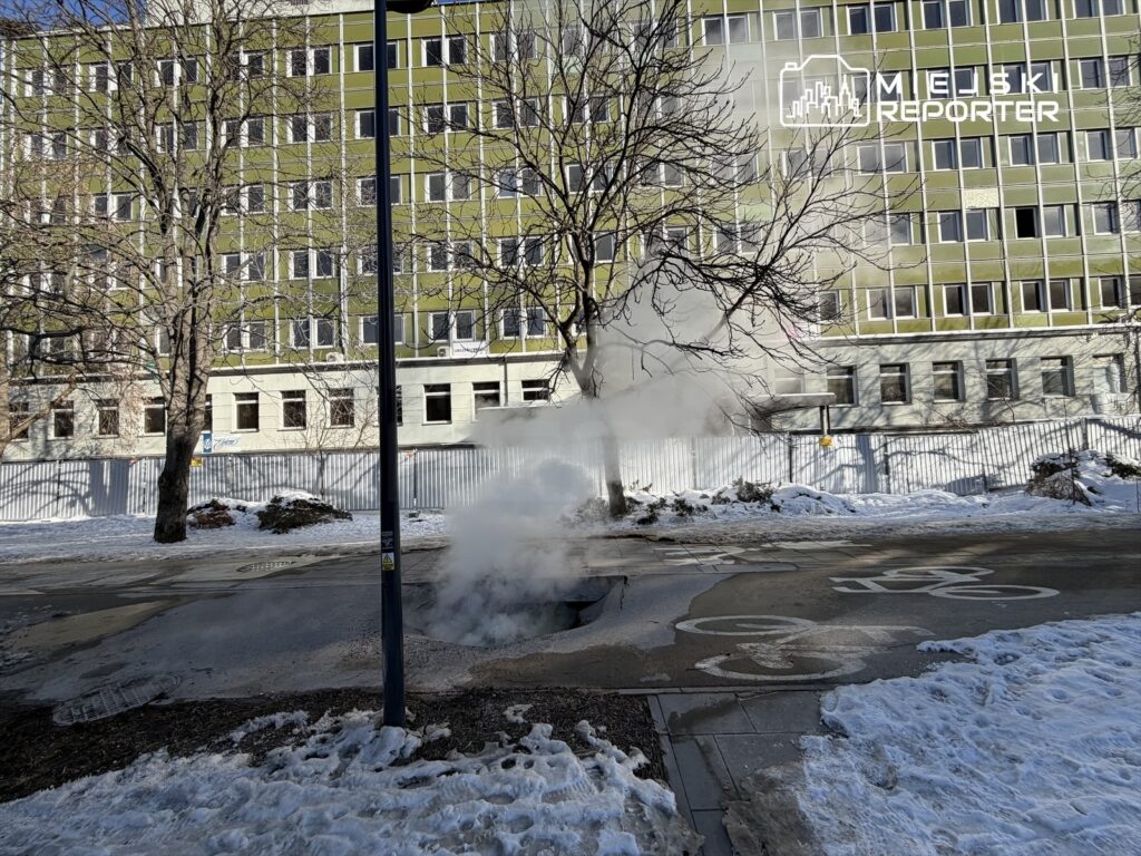 Para wydobywająca się z ulicy w pobliżu nowoczesnego biurowca, otoczonego śniegiem i drzewami.