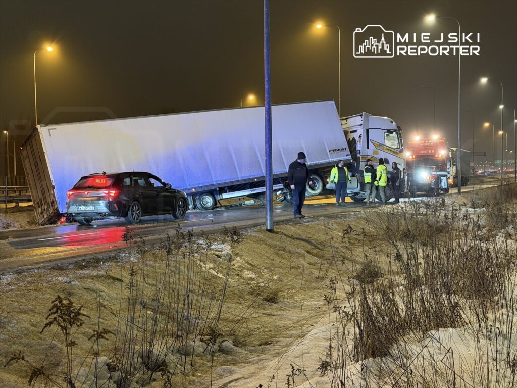 W nocy na drodze, zespół ratunkowy pracuje nad usunięciem przewróconej ciężarówki, obok stoi radiowóz.