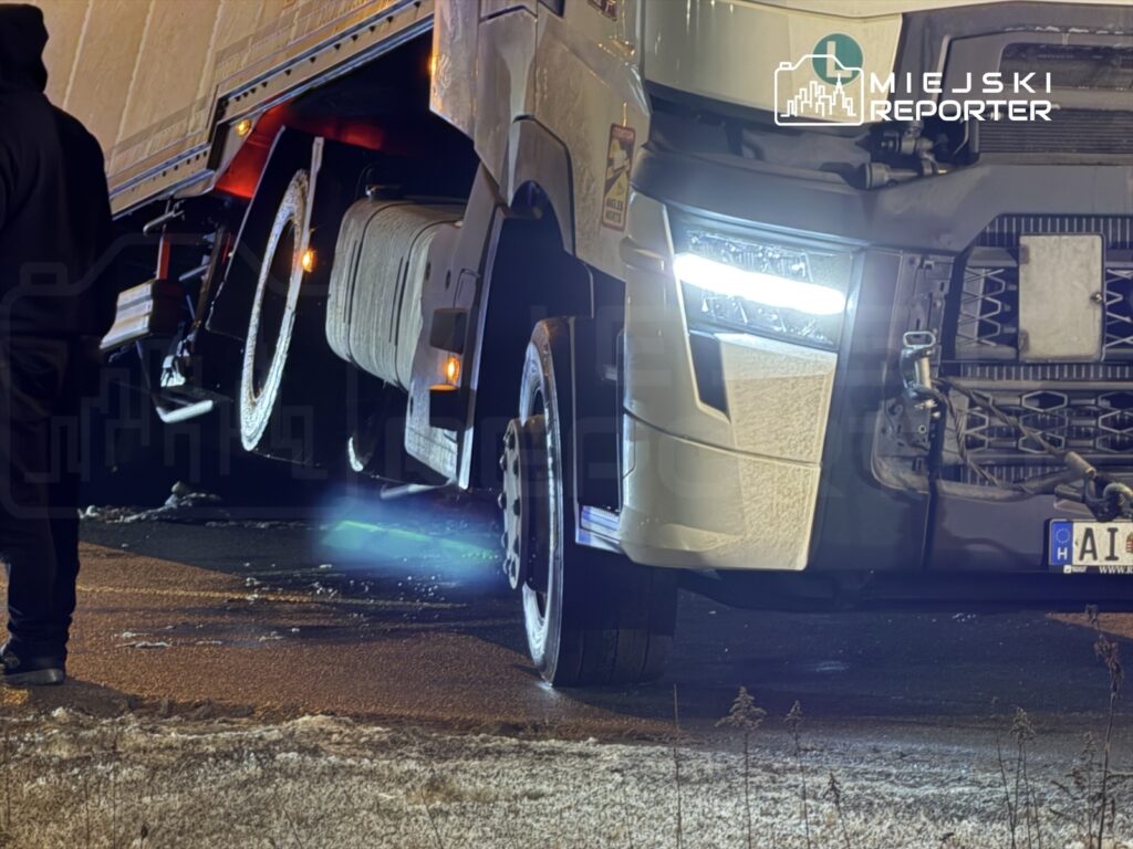 Ciężarówka z oświetleniem LED stoi na zaśnieżonej drodze, obok niej mężczyzna w czarnej kurtce.