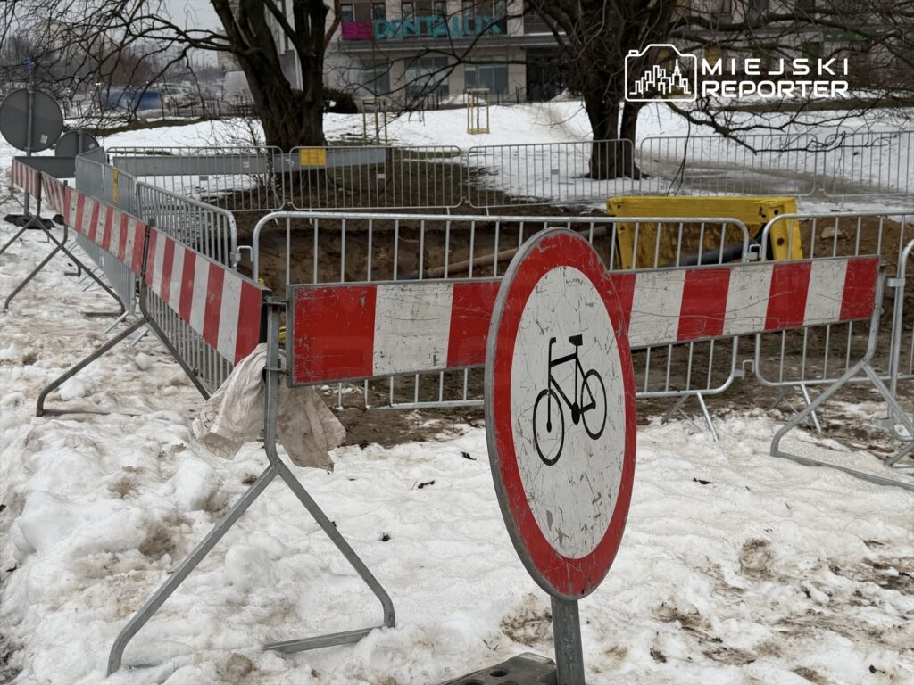 Znak zakazu wjazdu dla rowerów umieszczony obok ogrodzenia budowy na zaśnieżonym terenie.