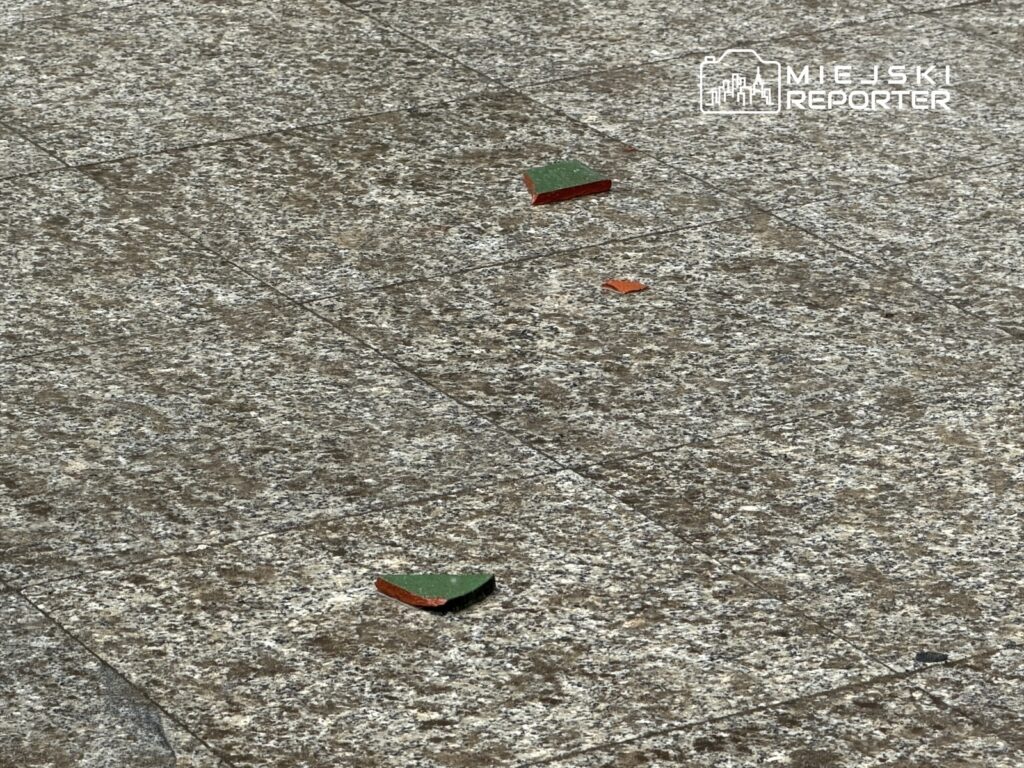 Na chodniku leżą fragmenty zielonego i czerwonego materiału.