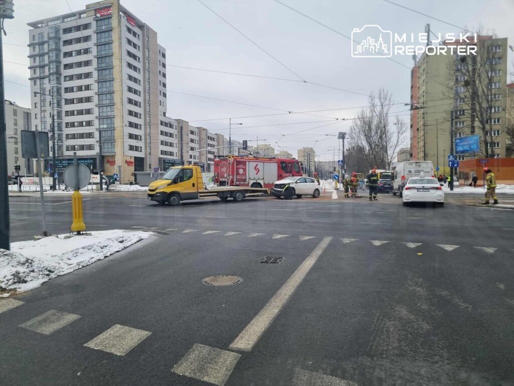 W miejscu wypadku drogowego z udziałem dwóch samochodów, strażacy i służby ratunkowe pracują nad zabezpieczeniem terenu.