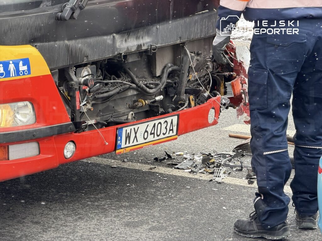 Uszkodzony autobus z widocznymi elementami silnika, obok pracownik w odzieży roboczej naprawiający pojazd.