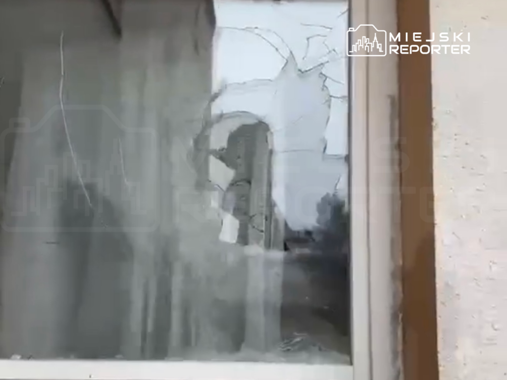 Pęknięte okno z widocznymi odpryskami szkła w opuszczonym budynku.