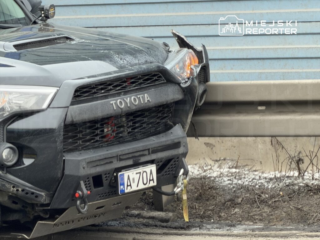 Czarny samochód terenowy marki Toyota z uszkodzoną przednią częścią zaparkowany na poboczu drogi.