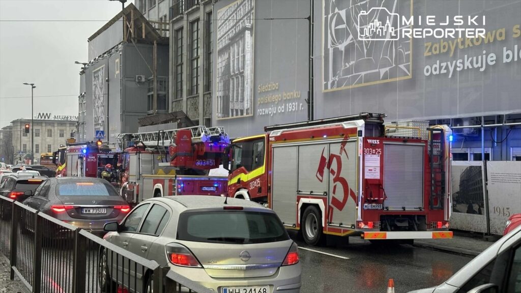 Wielka akcja ratunkowa z udziałem wozów strażackich na ruchliwej ulicy w deszczowy dzień.