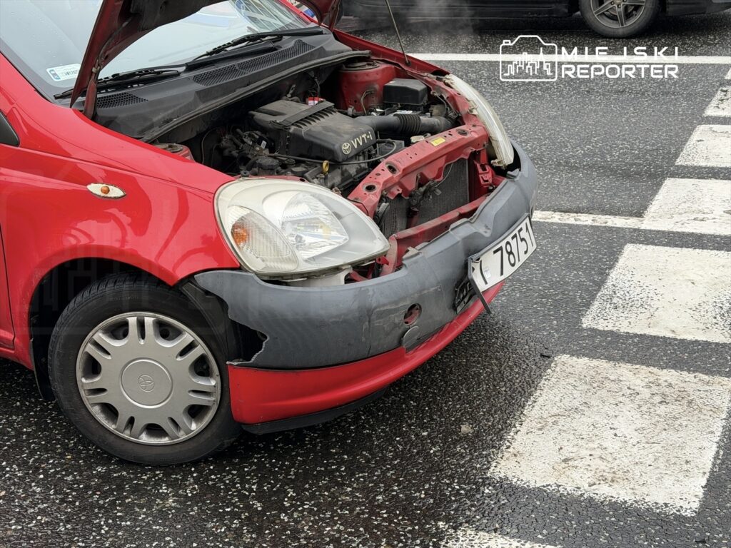 Czerwony samochód osobowy z otwartą maską stoi na pasach, wydobywając się z niego para.