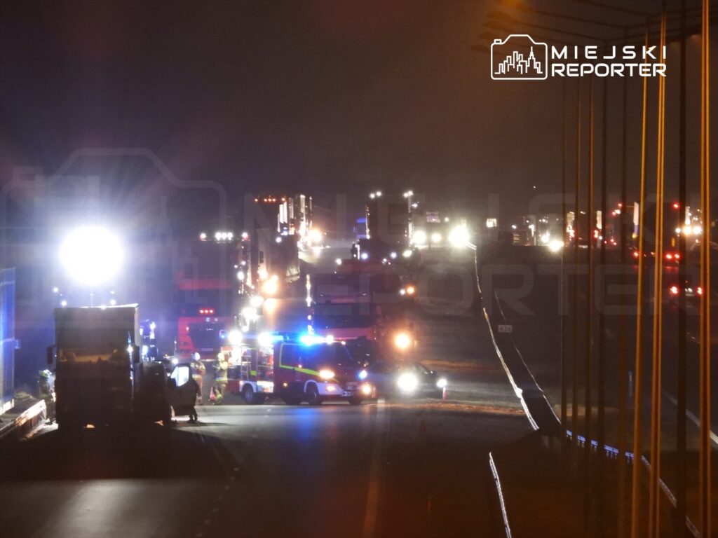 Na drodze nocą zablokowane są pojazdy, a służby ratunkowe prowadzą działania przy wypadku.