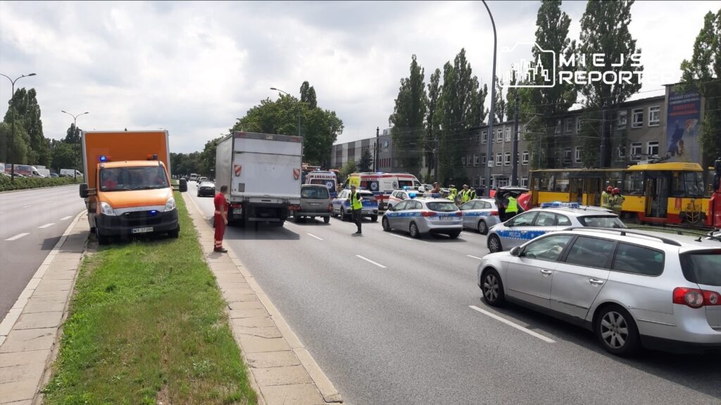 Na drodze odbywa się akcja służb ratunkowych, w tym karetki i policja, przy zablokowanym ruchu.