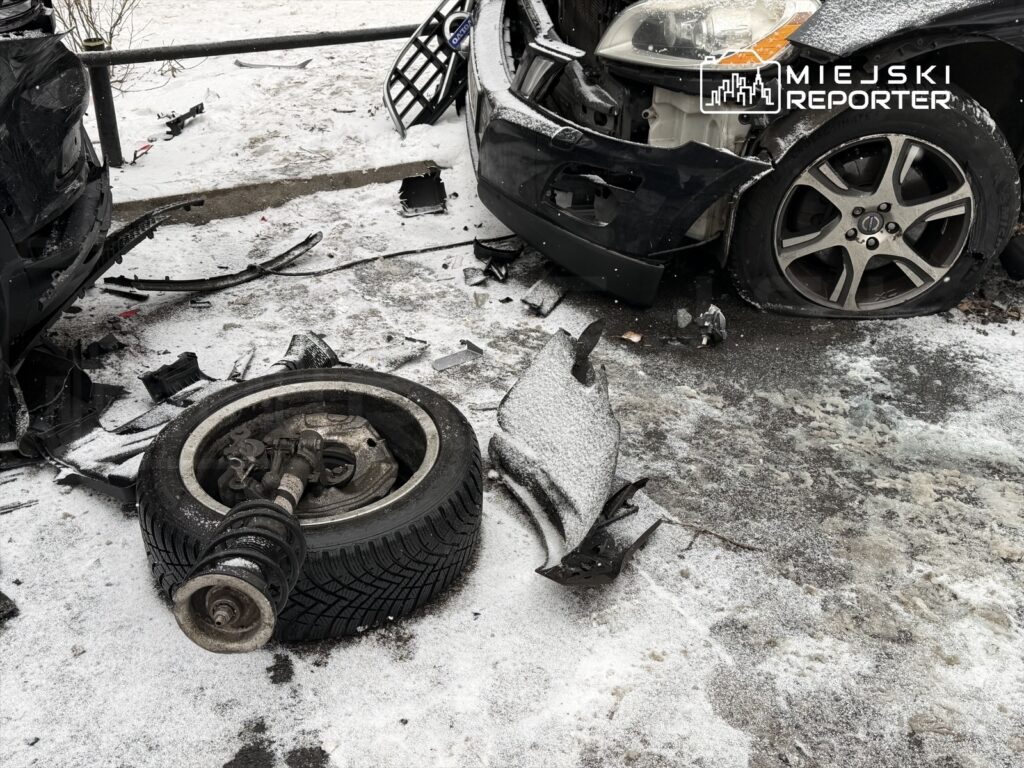 Zniszczone pojazdy leżą na zaśnieżonej nawierzchni, wokół rozrzucone fragmenty karoserii i opona z zawieszeniem.