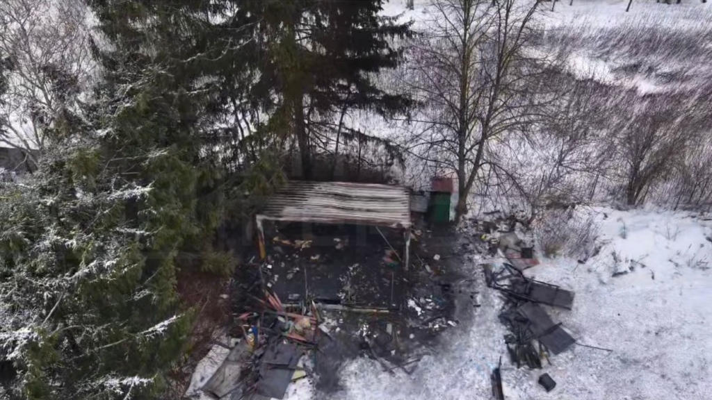 Zdewastowana altana otoczona śniegiem, z porozrzucanymi odpadkami i zniszczonymi elementami konstrukcyjnymi.