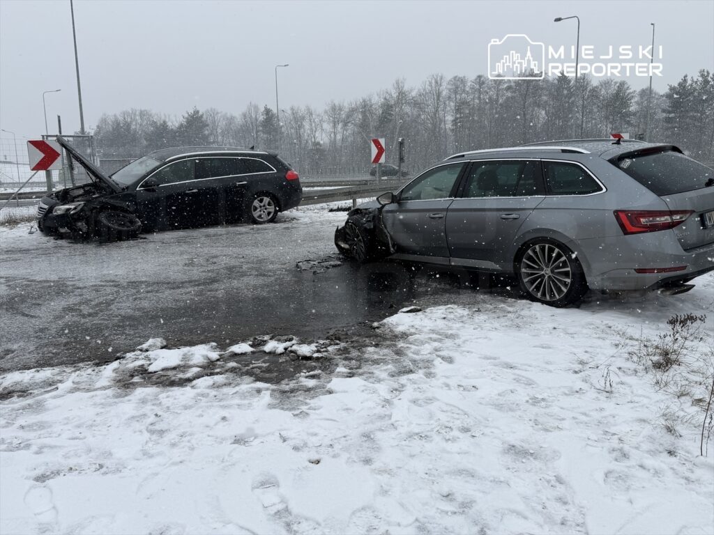 Dwa uszkodzone samochody osobowe na śliskiej drodze w trakcie opadów śniegu, jeden z otwartą maską.