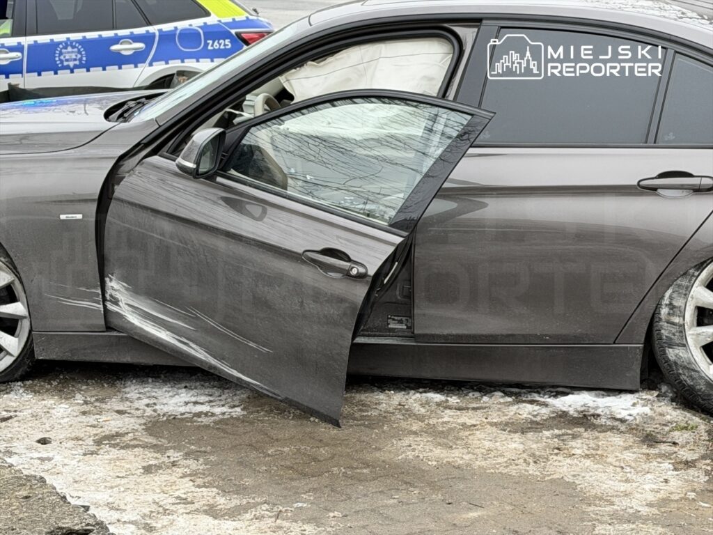 Uszkodzony samochód osobowy z otwartymi drzwiami, z widocznymi zarysowaniami na drzwiach, zaparkowany na śnieżnym podłożu.