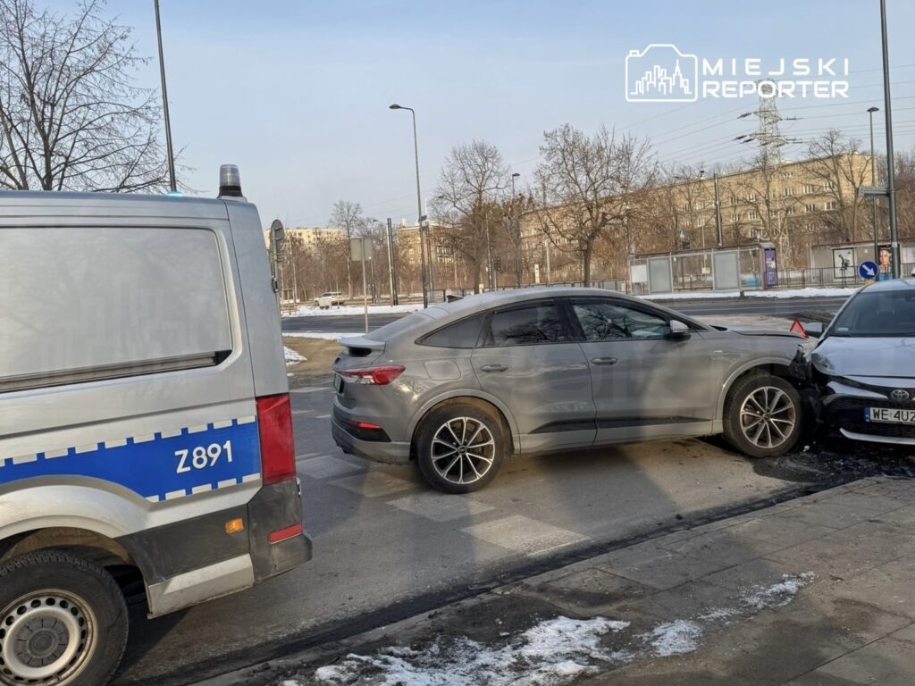 Zderzenie dwóch samochodów osobowych na skrzyżowaniu, obok stoi radiowóz policyjny.