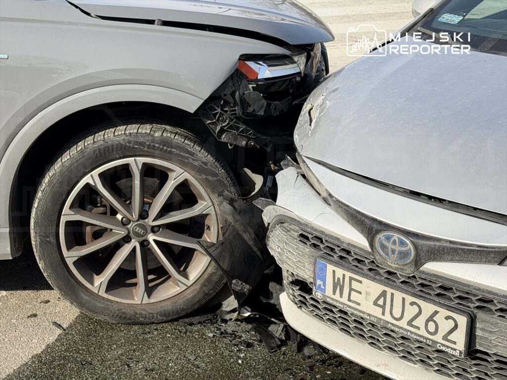 Dwa uszkodzone samochody osobowe zderzone na drodze, widoczna uszkodzona karoseria i opony.