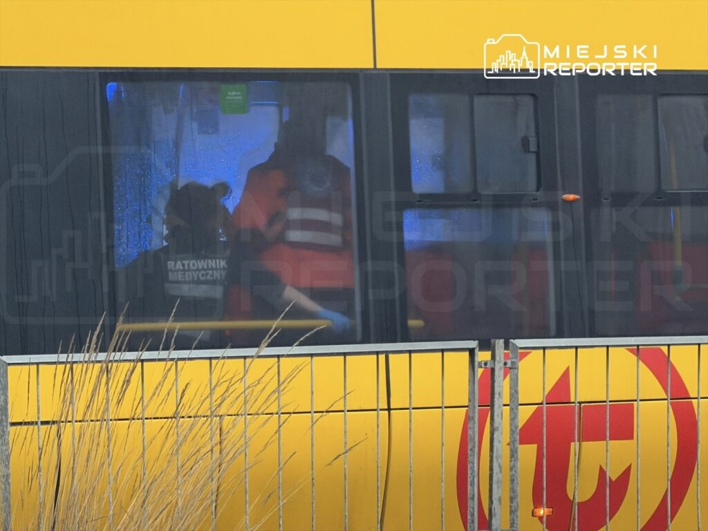 Ratownik medyczny w odblaskowej kamizelce pracuje wewnątrz karetki, obok drugiego członka zespołu.