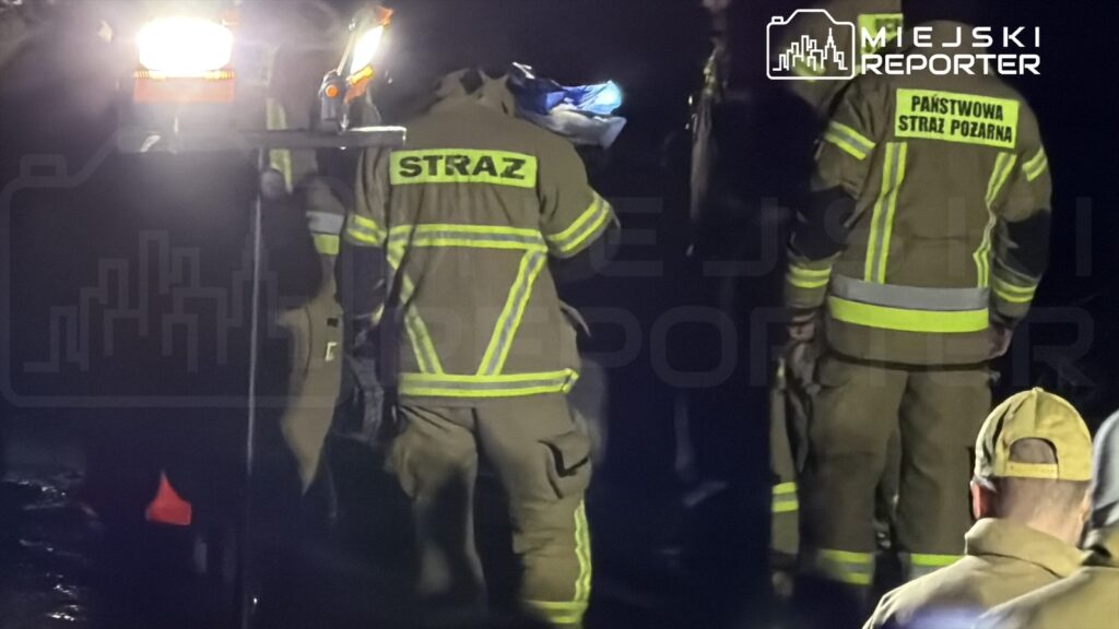 Strażacy w specjalistycznych strojach prowadzą akcję ratunkową w ciemnym otoczeniu.