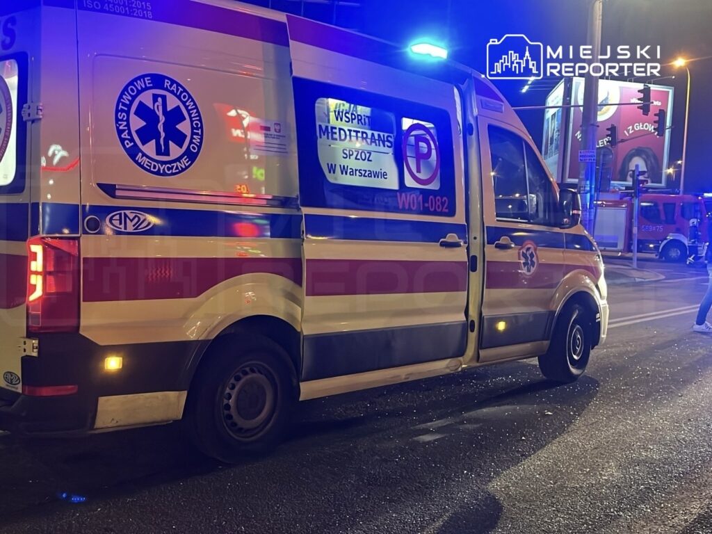 Karetka pogotowia z włączonymi światłami sygnalizacyjnymi stoi na ulicy w nocy.