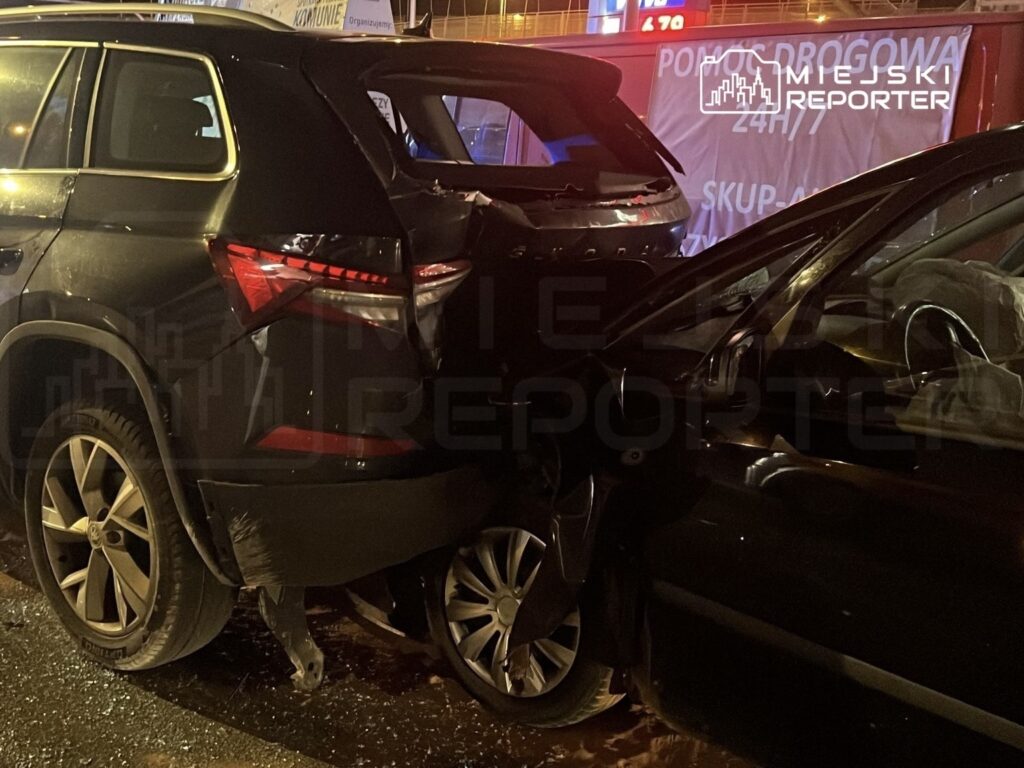 Dwa samochody osobowe zderzone na ulicy, jeden z nich ma uszkodzone tylne nadwozie, a drugi boczne.