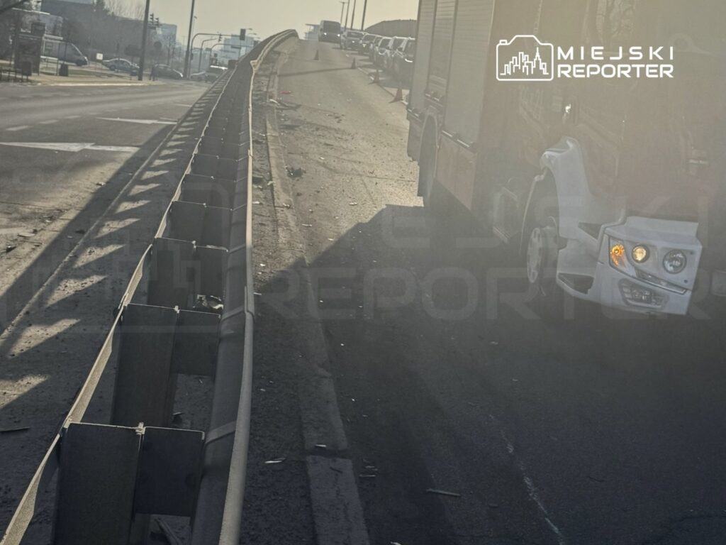 Uszkodzony pojazd ciężarowy stojący na poboczu drogi, obok bariery ochronnej, w słoneczny dzień.