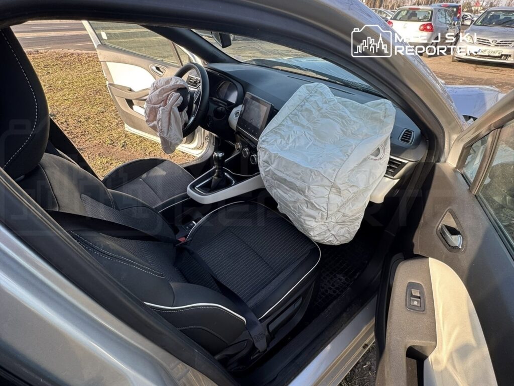 Wnętrze samochodu z otwartymi drzwiami, w którym widać rozłożoną poduszkę powietrzną na kierownicy.