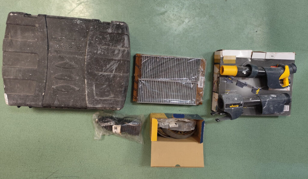 Zestaw narzędzi i akcesoriów remontowych rozłożony na zielonym podłożu, w tym walizka, filtr i pistolet malarski.