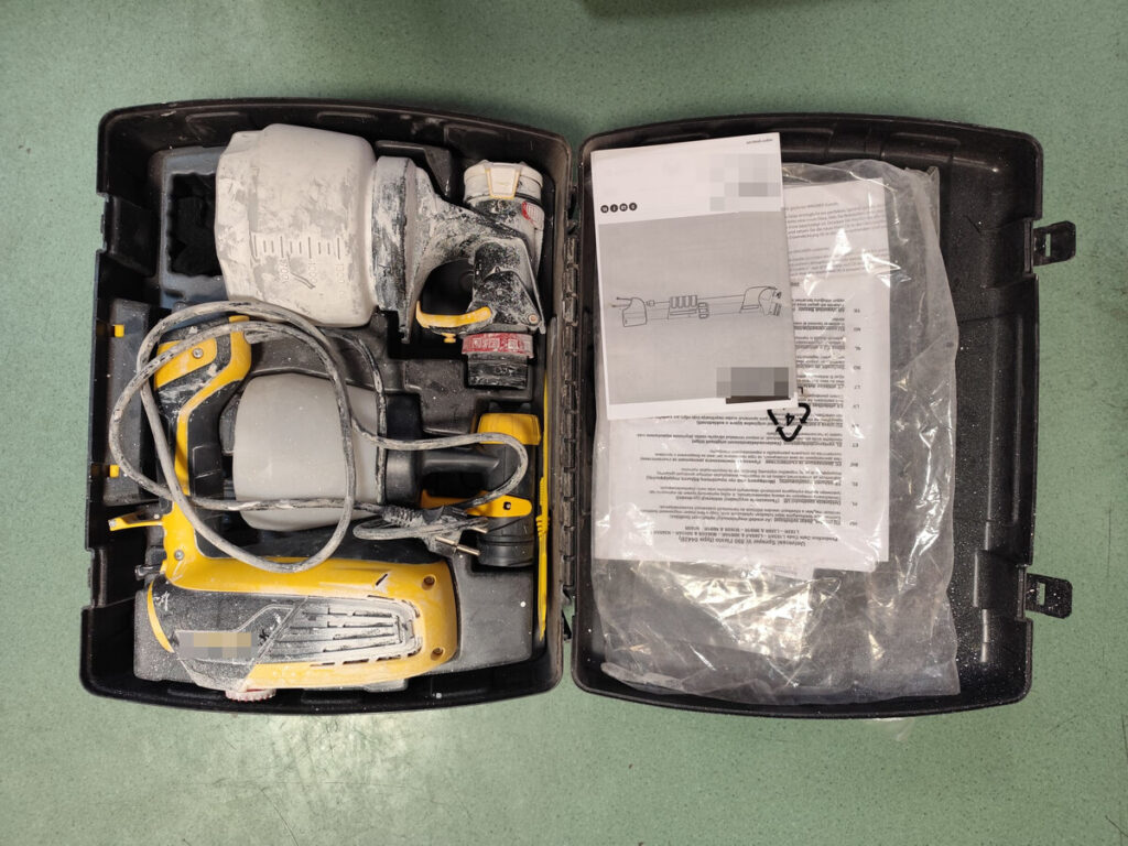 Zestaw narzędzi malarskich z pistoletem natryskowym, pojemnikami i instrukcją w zamkniętej walizce.