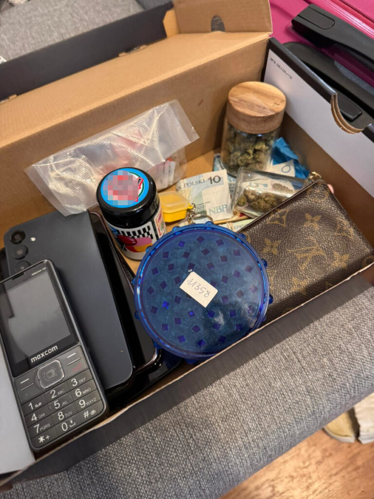 W kartonie znajdują się dwa telefony, słoik z zawartością, banknoty oraz małe pojemniki.