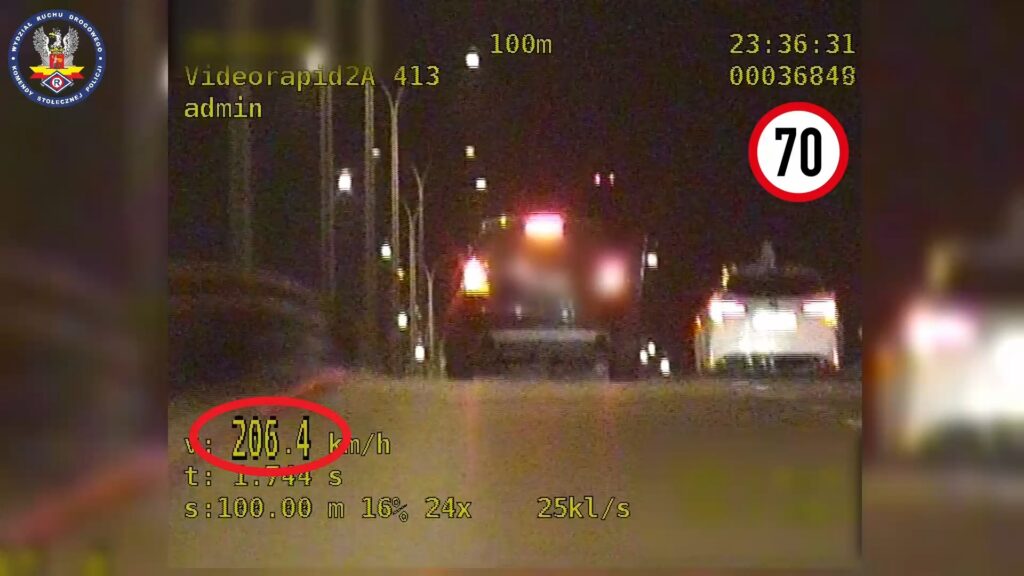 Pojazd poruszający się z prędkością 206,4 km/h na drodze, obok znaku ograniczenia prędkości do 70 km/h, w nocy.