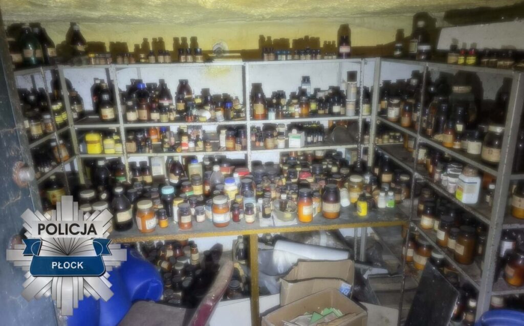 Zatłoczona piwnica z regałami pełnymi różnorodnych słoików i butelek chemicznych, w tle nieczytelne etykiety.