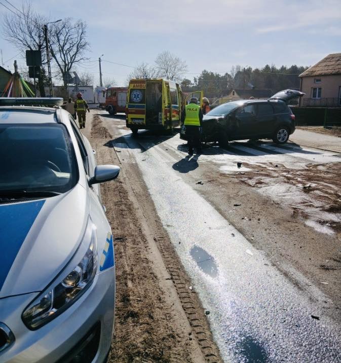 Na drodze dochodzi do wypadku; policjanci i ratownicy medyczni udzielają pomocy poszkodowanym.