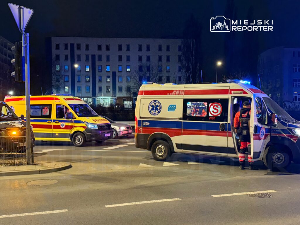 Zespół ratownictwa medycznego w ambulansie przygotowuje się do akcji na oświetlonej ulicy nocą.