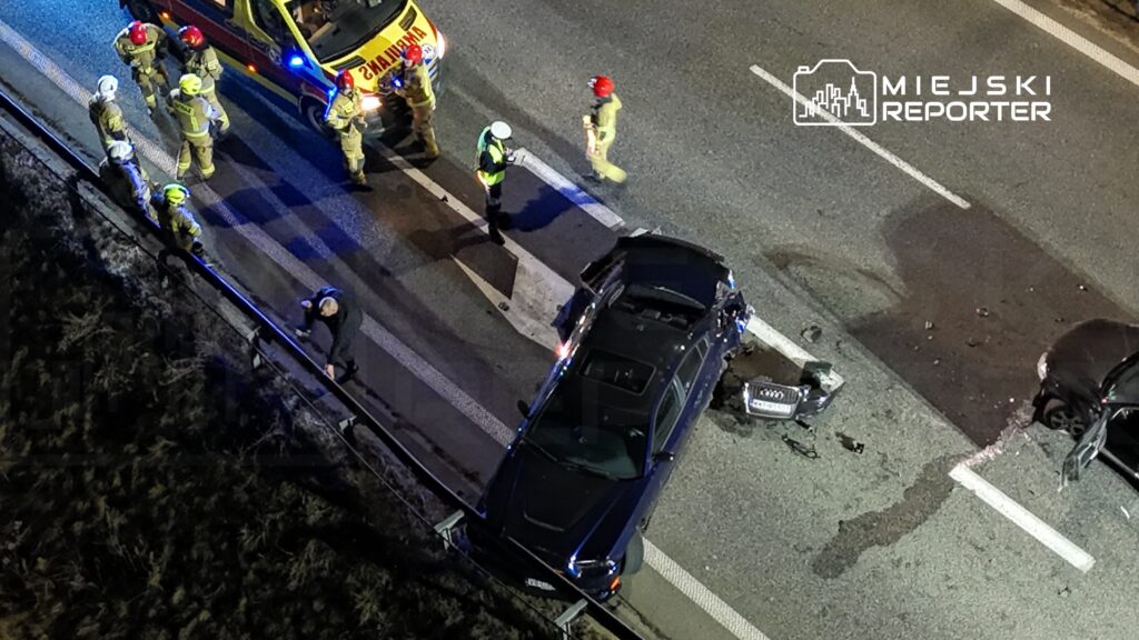 Ratownicy medyczni i strażacy udzielają pomocy na miejscu wypadku drogowego z udziałem dwóch uszkodzonych pojazdów.