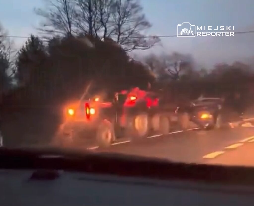 Ciężarówka z przyczepą poruszająca się po drodze w otoczeniu drzew podczas zmierzchu.