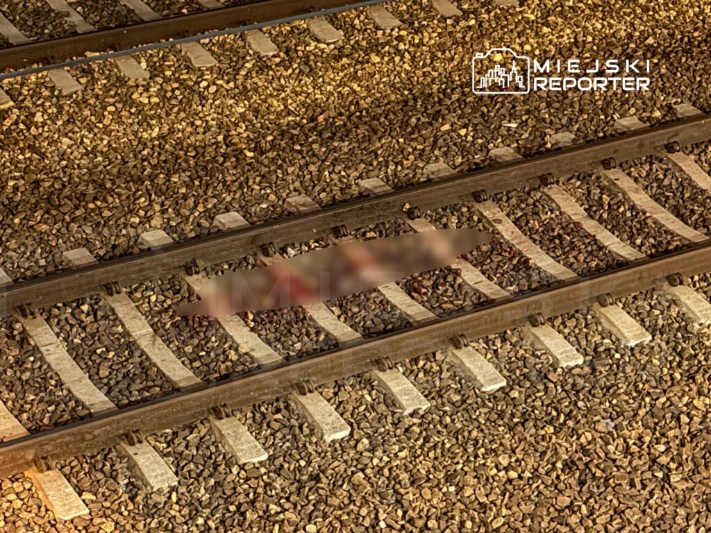 Na torach kolejowych widoczny jest cień, leżący na kamieniach między szynami.