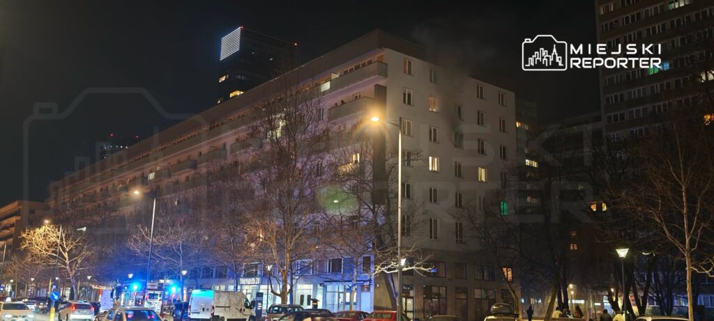 Pożar w budynku mieszkalnym, z dymem wydobywającym się z okna na trzecim piętrze, w nocy w mieście.