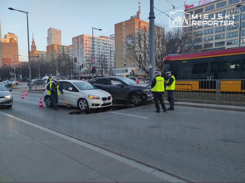 Policjanci zabezpieczają miejsce wypadku drogowego z udziałem dwóch samochodów na ulicy w mieście.
