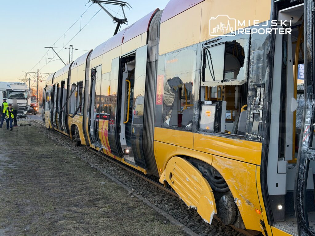 Zdewastowany tramwaj z uszkodzoną kabiną stoi na torach, obok pracują ratownicy i strażacy.