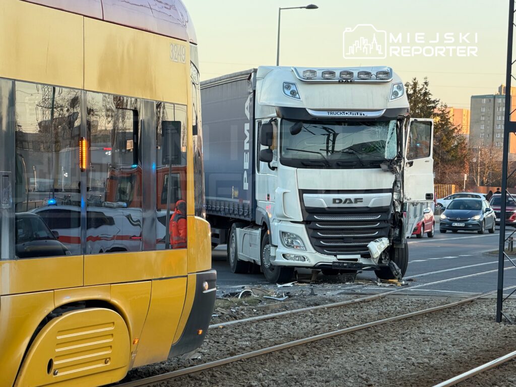 Złomowany ciężarówka DAF z uszkodzoną przednią częścią stoi obok tramwaju na torach w miejskim otoczeniu.