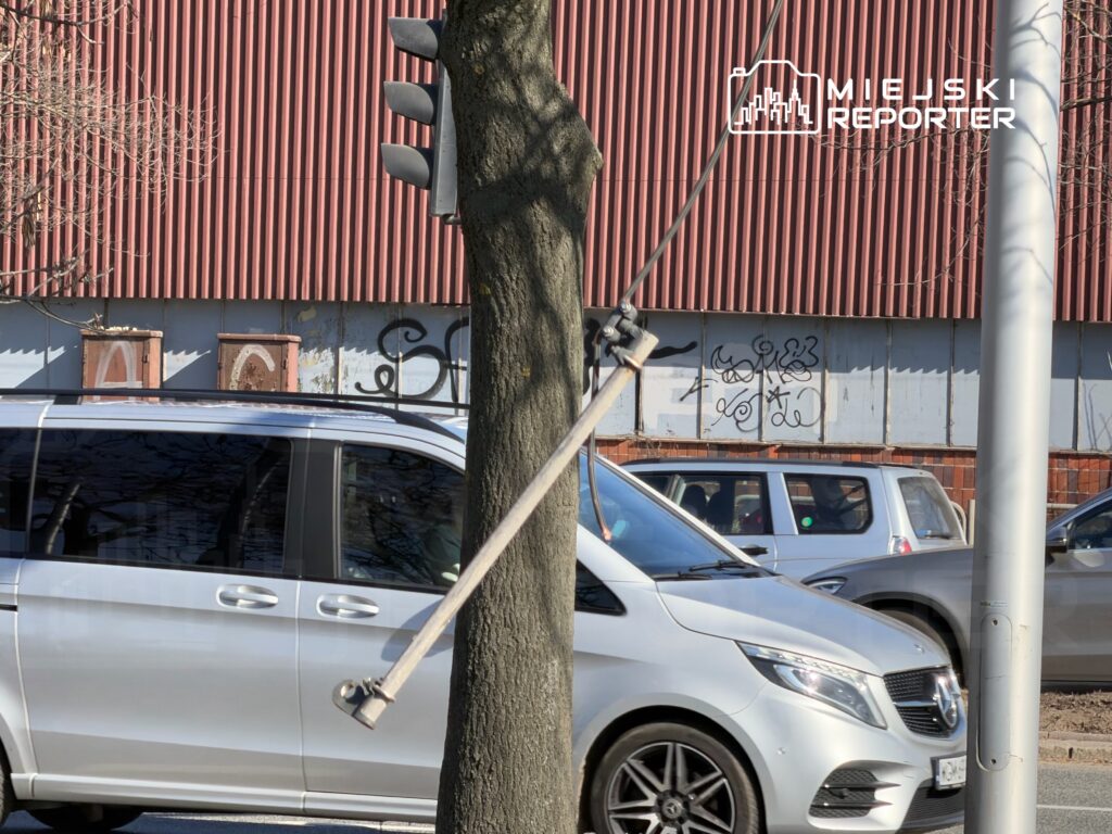 Zielone światło na sygnalizatorze świetlnym obok ruchliwej ulicy, z samochodami przejeżdżającymi obok.