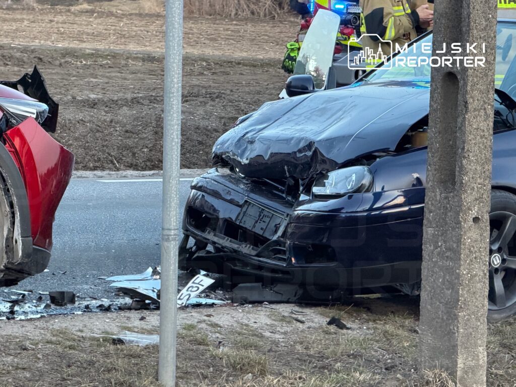 Zderzenie dwóch samochodów osobowych na drodze, jeden z nich mocno uszkodzony z wgniecionym przodem.