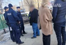 Grupa policjantów rozmawia z kilkoma osobami na chodniku w miejskim otoczeniu.