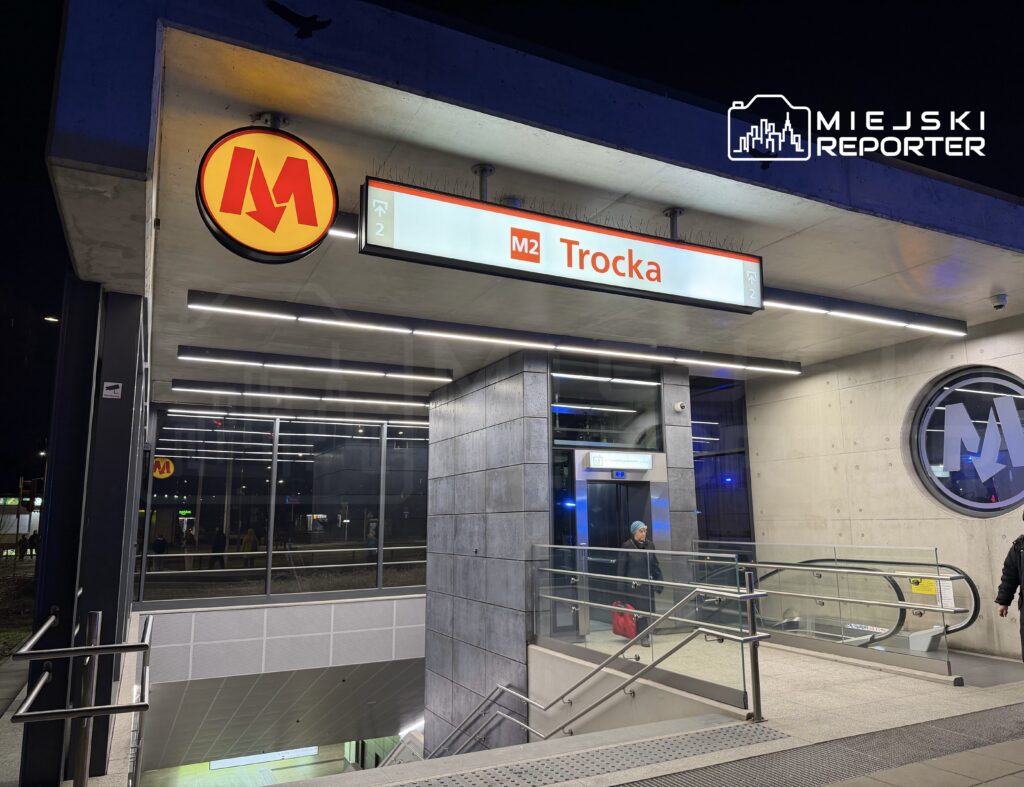 Stacja metra z logo M i oznaczeniem "Trocka", oświetlona nowoczesnymi lampami LED.