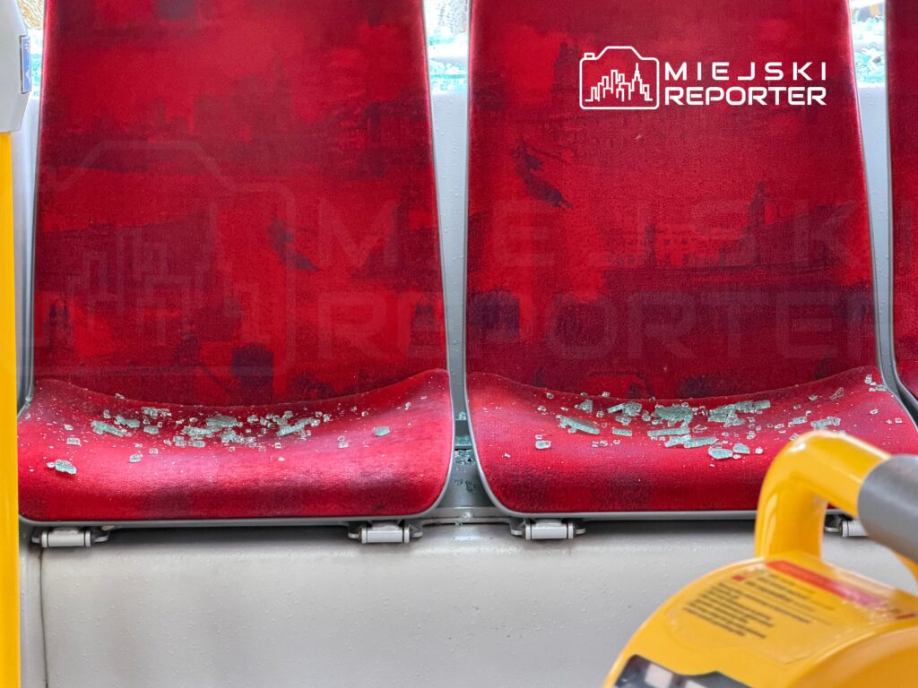 Zabrudzone siedzenia w autobusie pokryte odłamkami szkła.