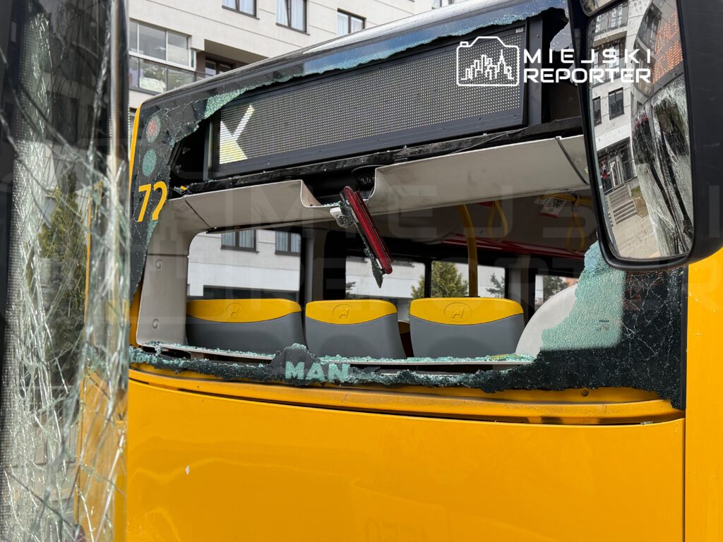 Uszkodzony przód żółtego autobusu miejskiego z wybitymi szybami i widocznymi siedzeniami wewnątrz.