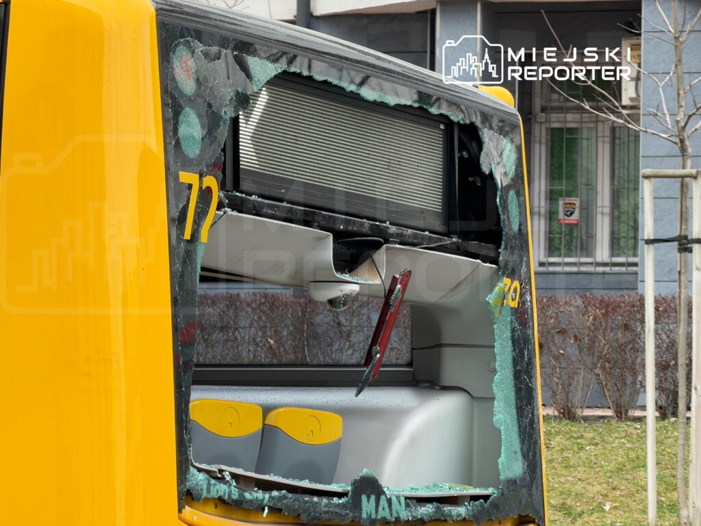 Uszkodzony tył autobusu miejskiego z wybitymi szybami, widać numer 72 i fragmenty szkła na podłodze.