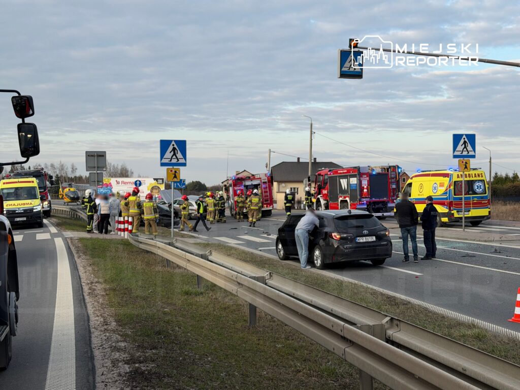 Na drodze doszło do wypadku; zespoły ratownicze i strażacy udzielają pomocy poszkodowanym przy uszkodzonym pojeździe.