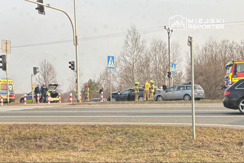 Na skrzyżowaniu stoją dwa uszkodzone samochody, obok nich pracują strażacy i ratownicy medyczni.